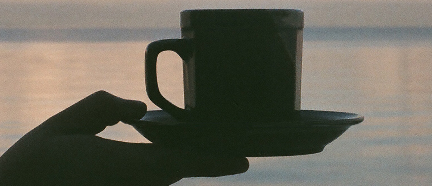 Hand holding coffee mug and saucer