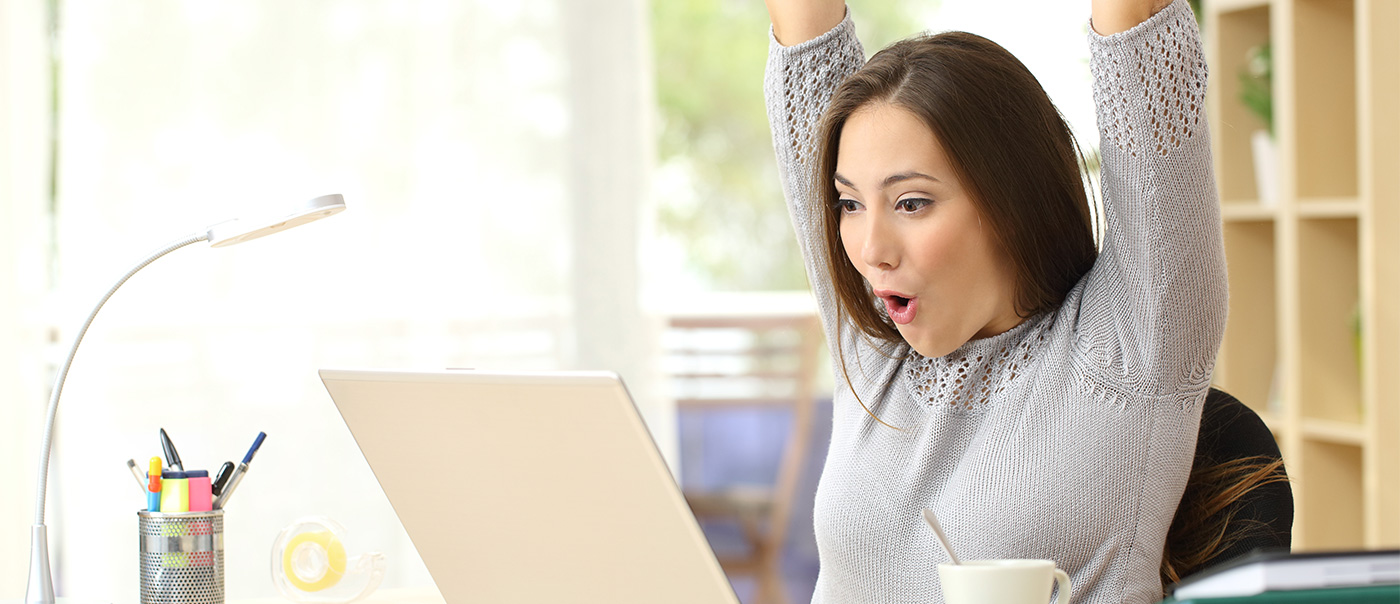 Woman showing excitement in front of laptop