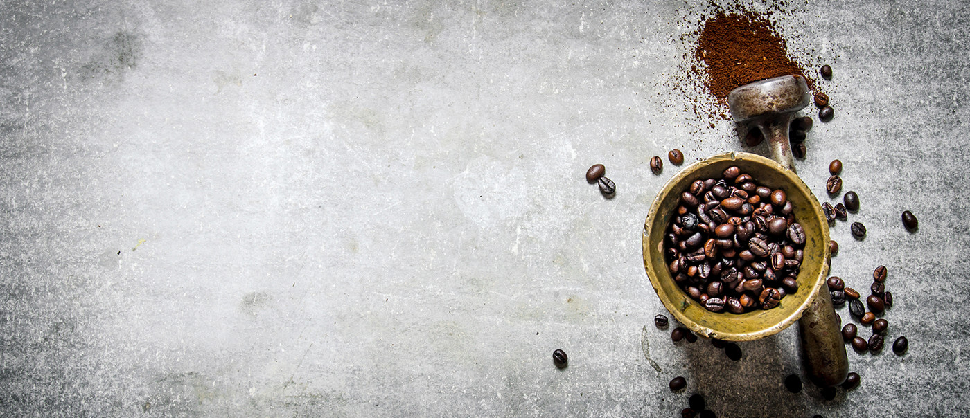 Cup with coffee beans over a grey backdrop
