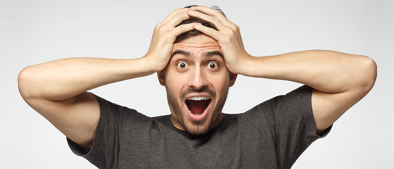 A man holds his head with a shocked expression on his face