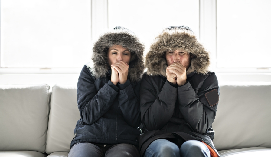 Cold couple wearing winter coats inside