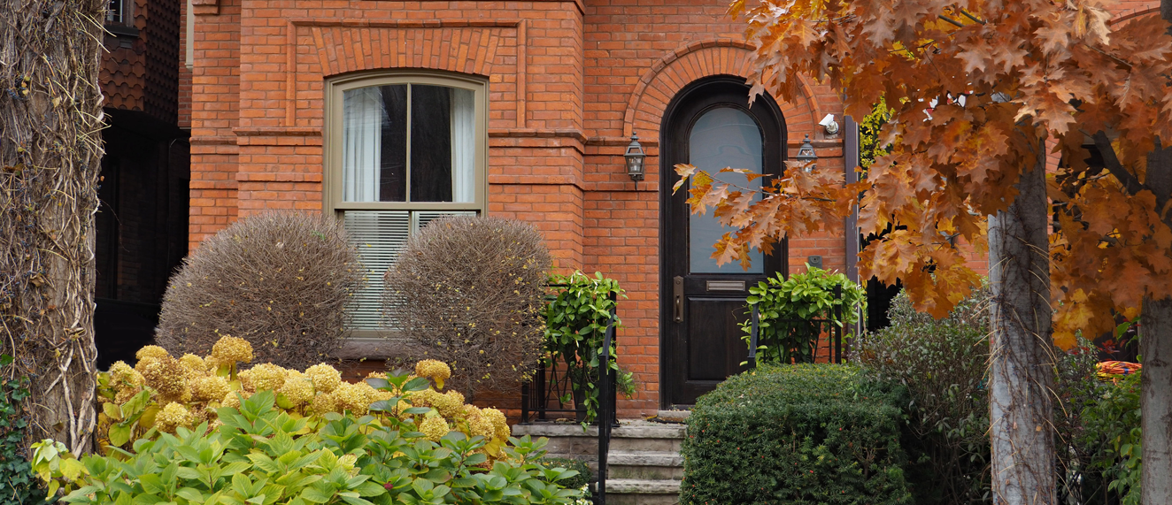A red brick house surrounded by fall leaves.