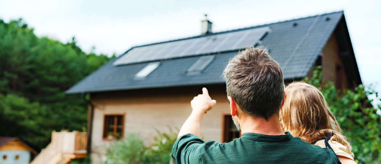 Man and child pointing at home with solar panels.
