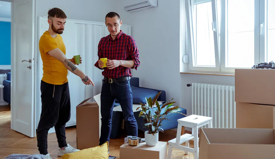 Two men standing in room with boxes.