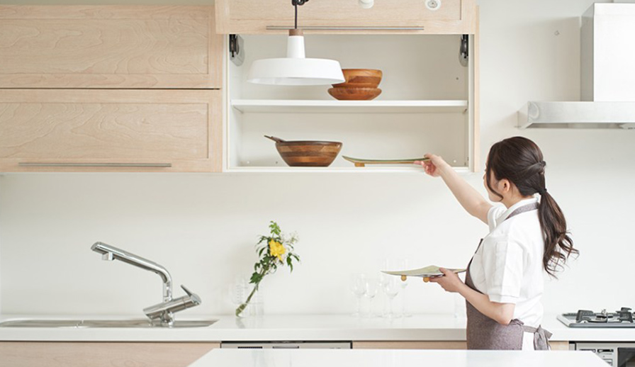 Woman putting plates away in kitchen.