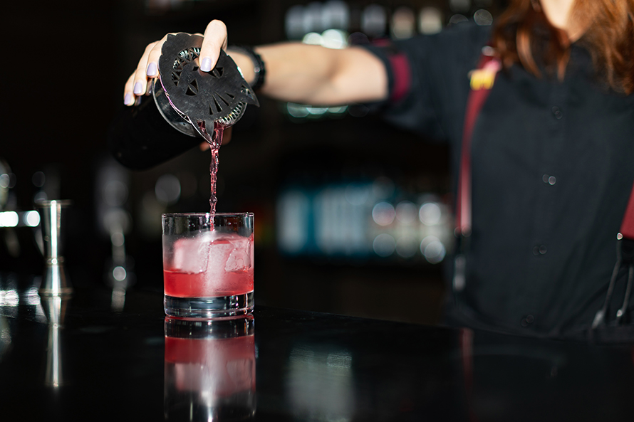 Person pouring a cocktail.