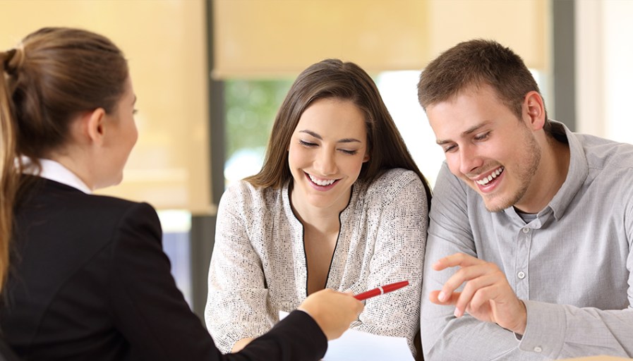 Couple smiling while talking to real estate agent