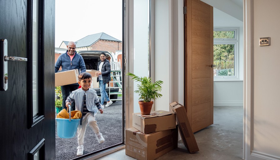 Family going into home with moving boxes.